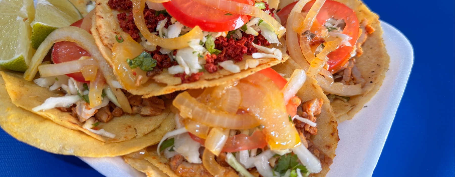 Tacos de Tacos Manuel servidos con cebolla, tomate, col y limón